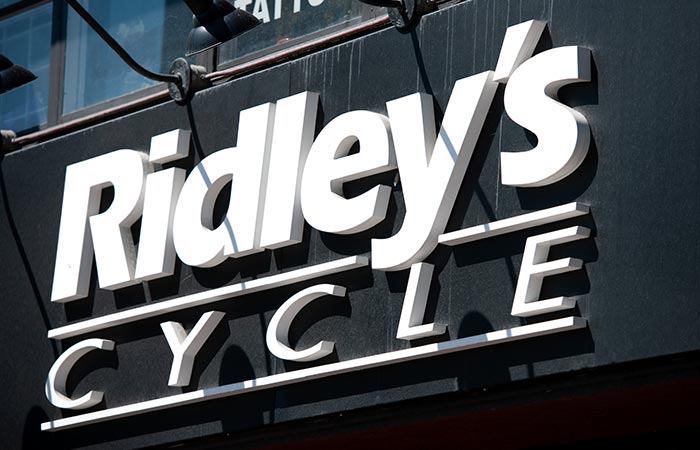 Exterior view of Ridley’s Cycle illuminated storefront sign, showcasing custom signage design by 54blue.